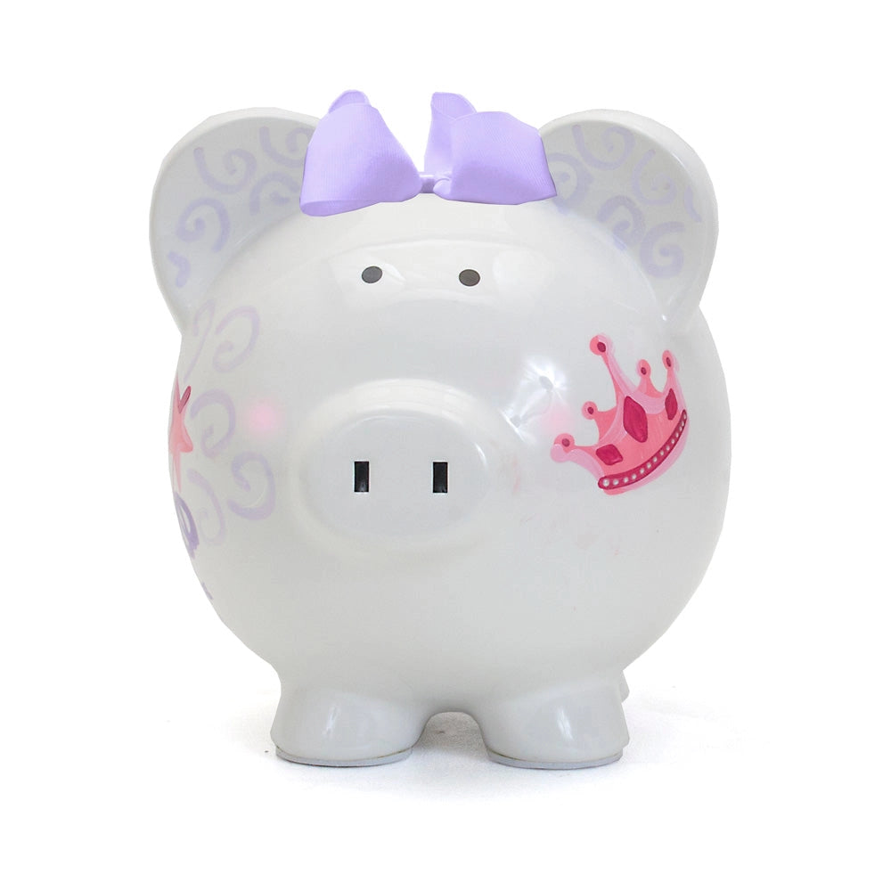 Front photo of a white piggy bank with a pink crown and  purple bow on on a white background