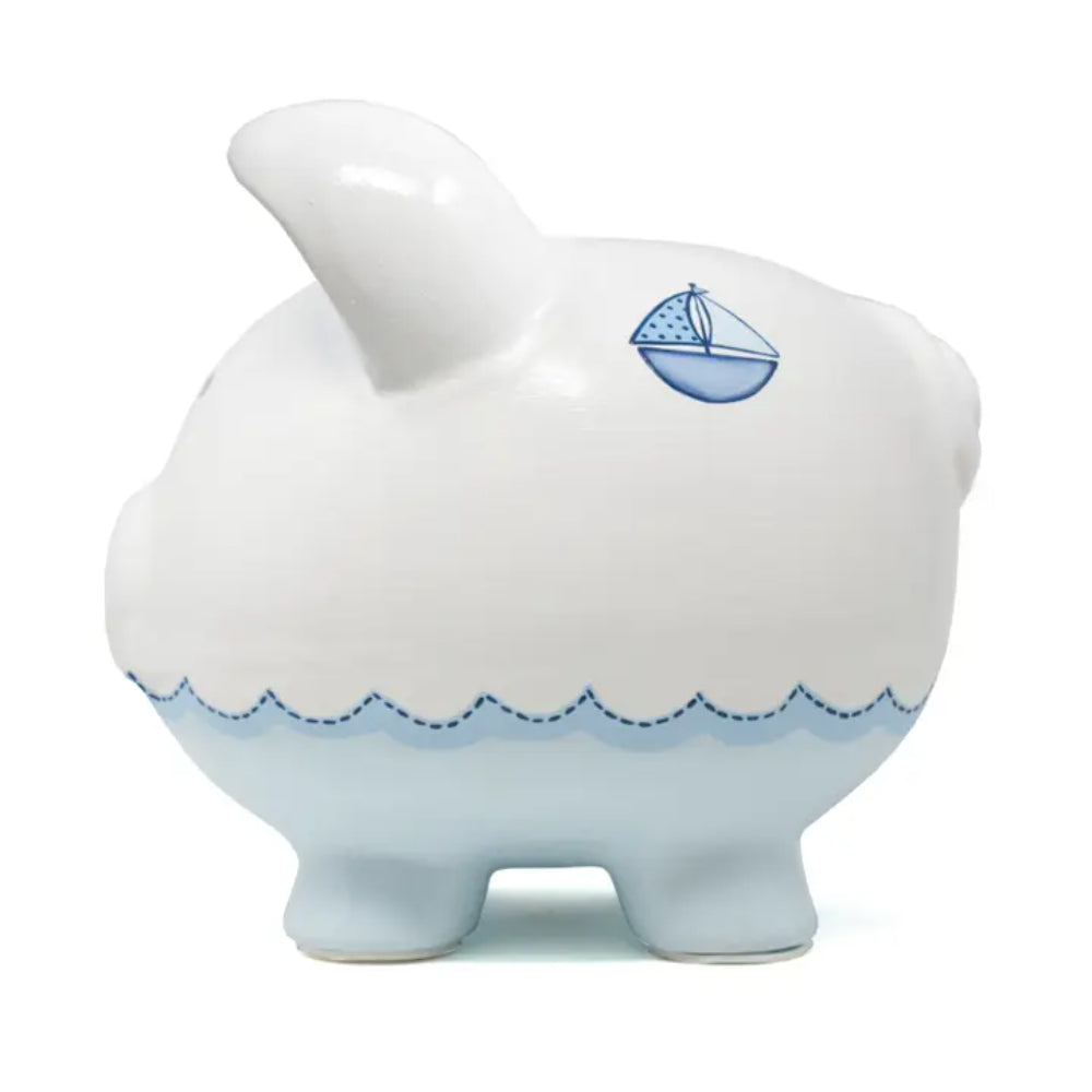 White ceramic piggy bank with blue accents and a sailboat design on a white background