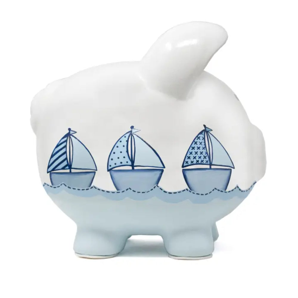 White piggy bank with blue accents and sailboat designs on a white background