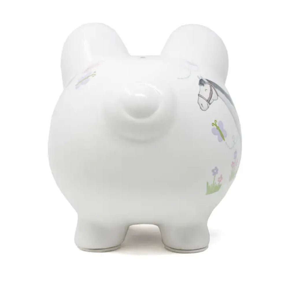 A white ceramic piggy bank with a glossy finish, decorated with delicate illustrations of a horse and small purple and green flowers on the side, shown against a plain white background.