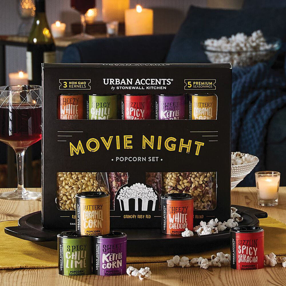 Movie night popcorn set with various flavors on a table with candles and wine.