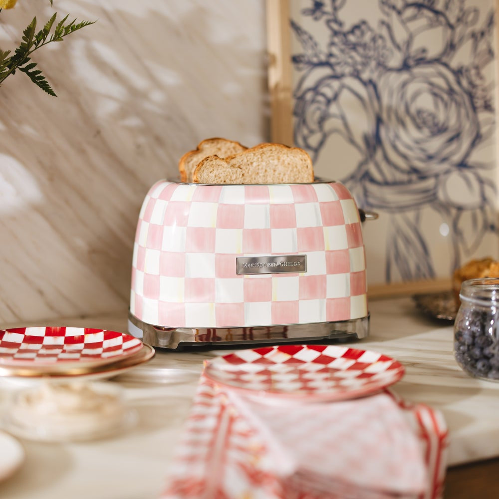 Pink and white checkered toaster with bread on a kitchen counter.