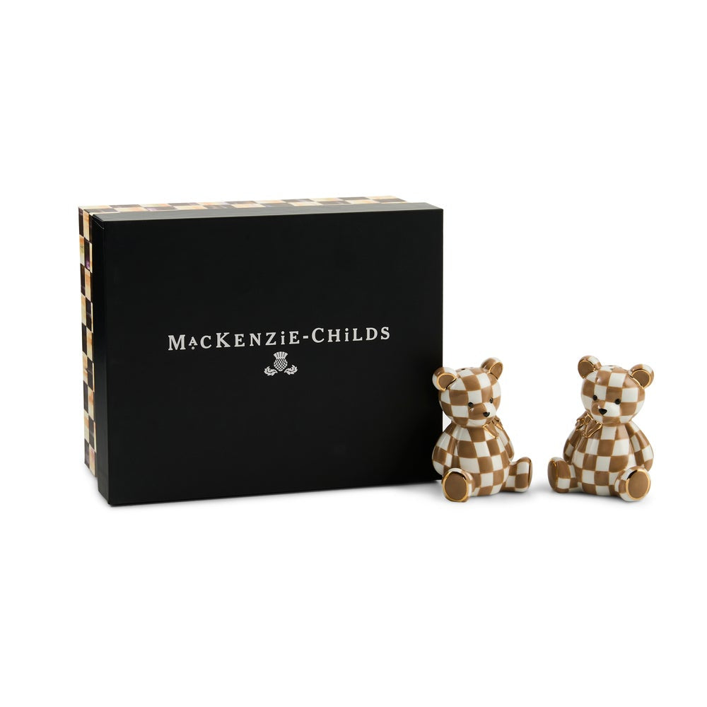 A pair of small checkered teddy bear figurines with a brown and cream checkerboard pattern, standing next to their black presentation box with the 'MACKENZIE-CHILDS' brand name printed in white.