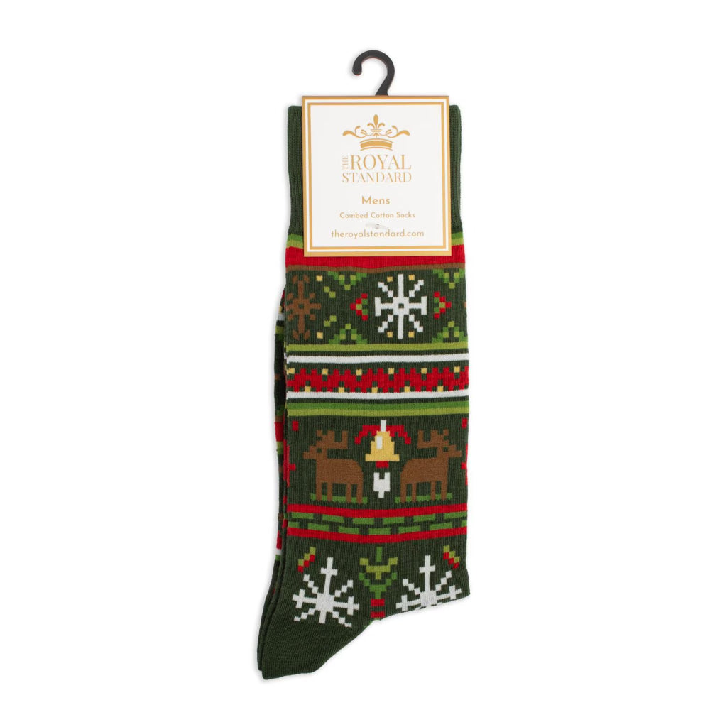 A pair of Christmas-themed knit socks hanging from a black plastic hanger with a paper brand label. The socks feature a dark green base with festive patterns including white snowflakes, red and green horizontal stripes, and brown reindeer with a small golden bell.