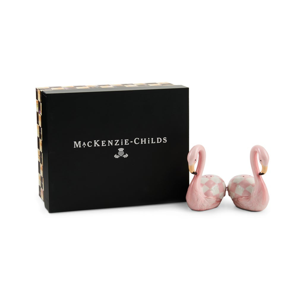 MacKenzie-Childs pink flamingo-shaped salt and pepper shakers next to their black presentation box on a white background.