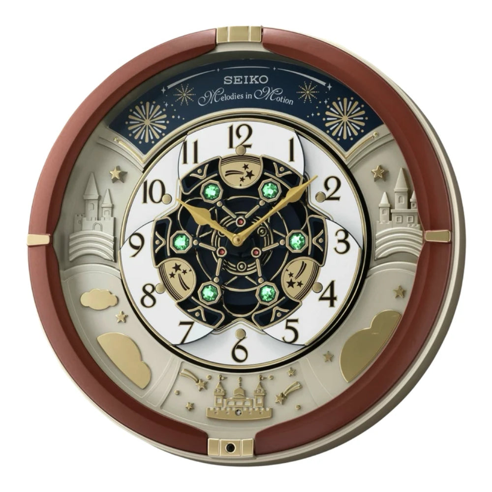 A Seiko Magic Kingdom wall clock featuring a circular design with castle motifs, gold-toned details, green gem accents, and a dark blue outer ring on a white background.