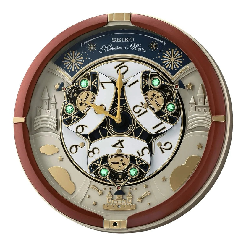A Seiko Monsters in Motion wall clock featuring a complex multilayered design with gold, white, and dark blue elements, green crystal accents, and castle motifs, shown against a plain white background.