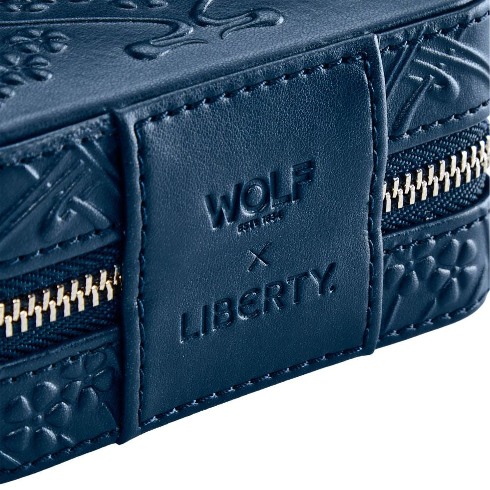Close-up of a blue leather wallet with 'Wolf & Liberty' branding.