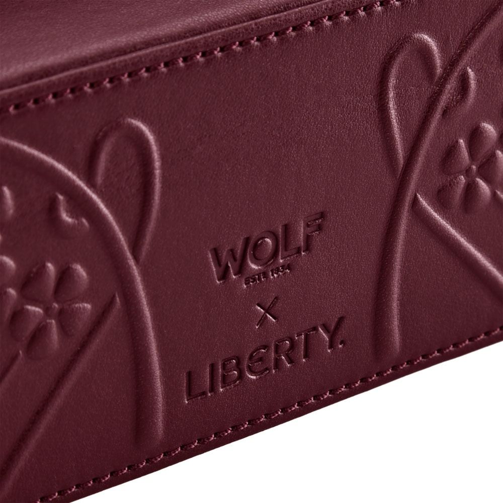 Close-up of a maroon leather product with 'Wolf & Gloria' and 'Liberty' branding.