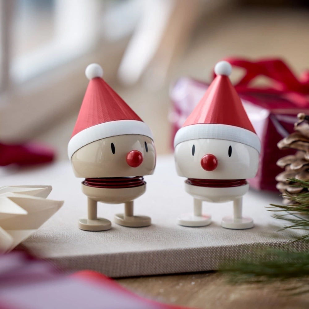 Two small Santa Claus figurines with red hats and white beards on a surface.