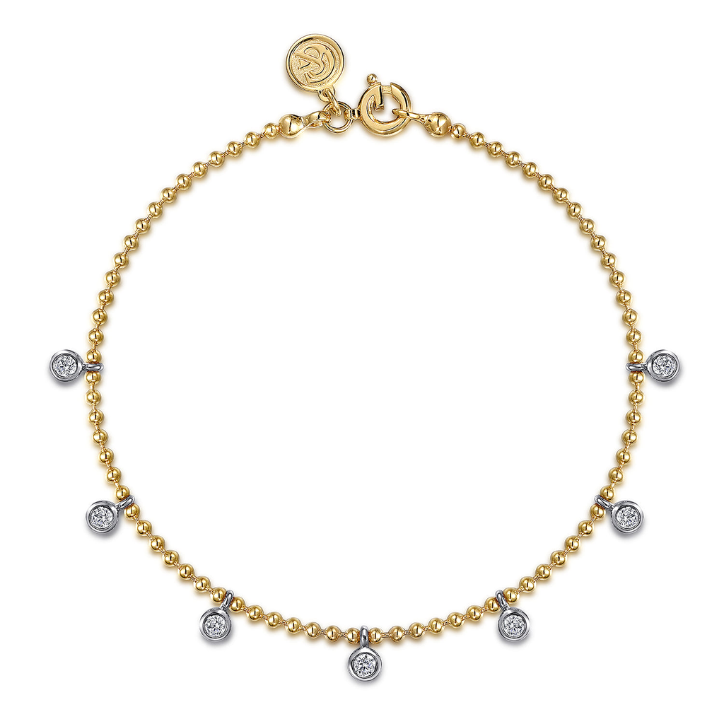 gold bracelet with white and silver droplets on white background