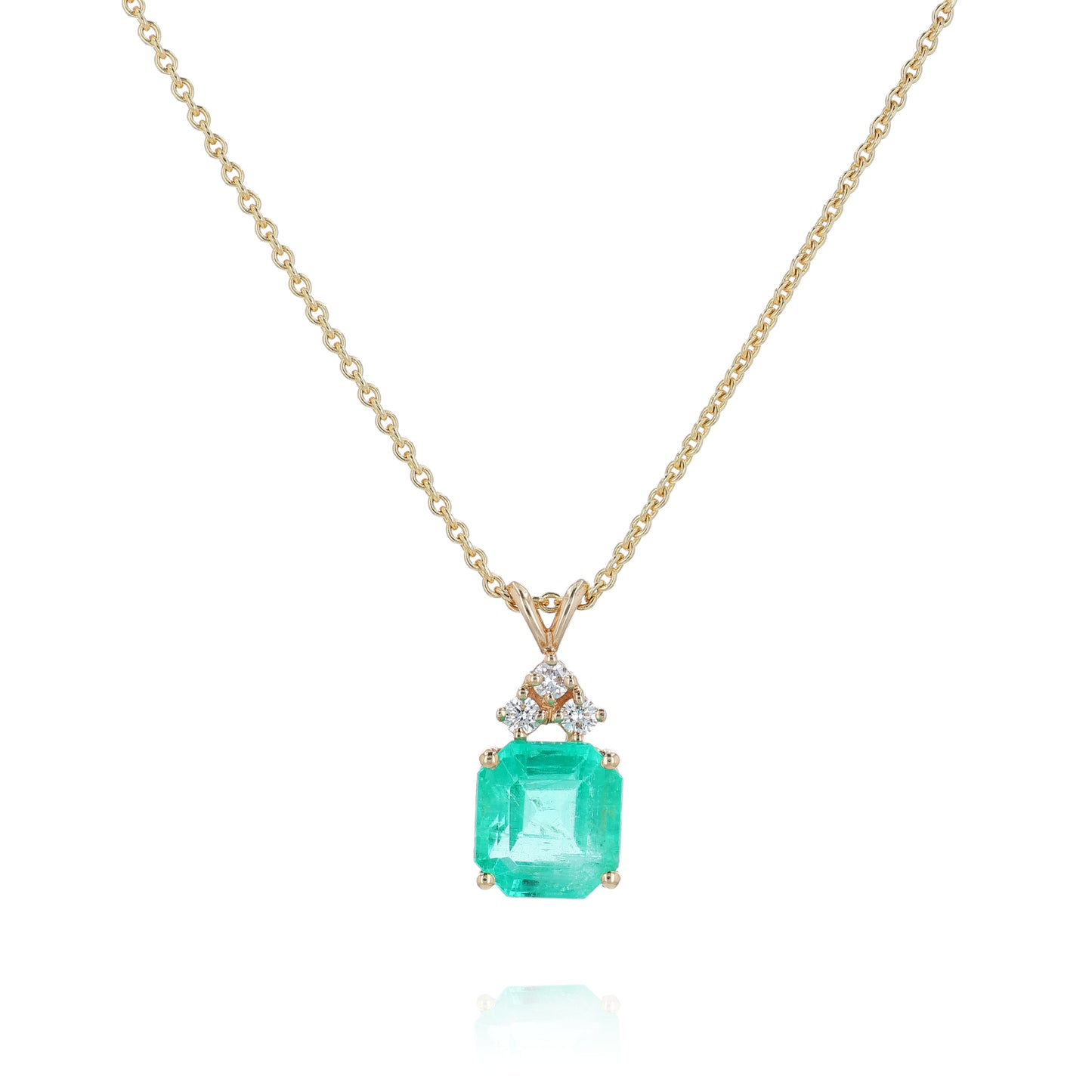 Yellow gold emerald cut emerald and diamond pendant necklace on a white background
