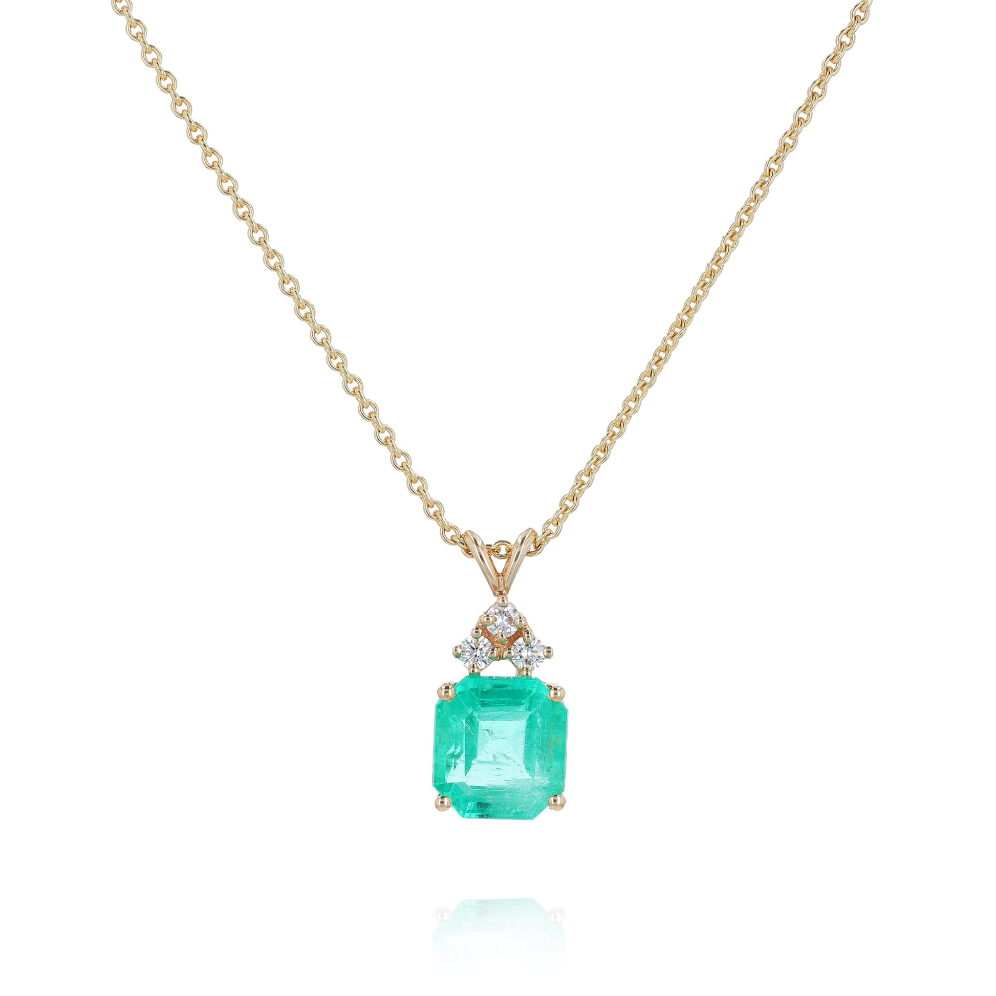 Yellow gold emerald cut emerald and diamond pendant necklace on a white background