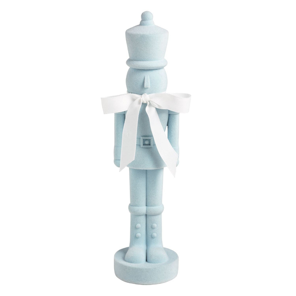 A light blue nutcracker figurine with a white bow around its neck, standing on a round base against a plain white background.