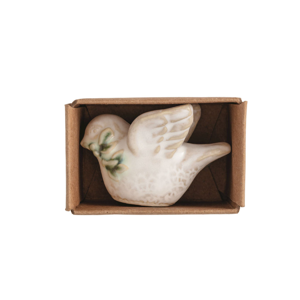 A small ceramic bird figurine with green leaf accents on its back, displayed inside a brown cardboard box against a white background.