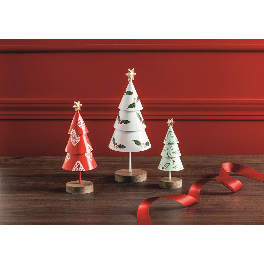 Three small Christmas trees on stands with a red ribbon against a red wall.
