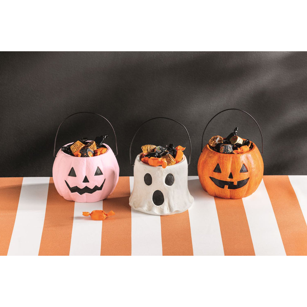 Three Halloween-themed candy buckets on a striped tablecloth with a black background