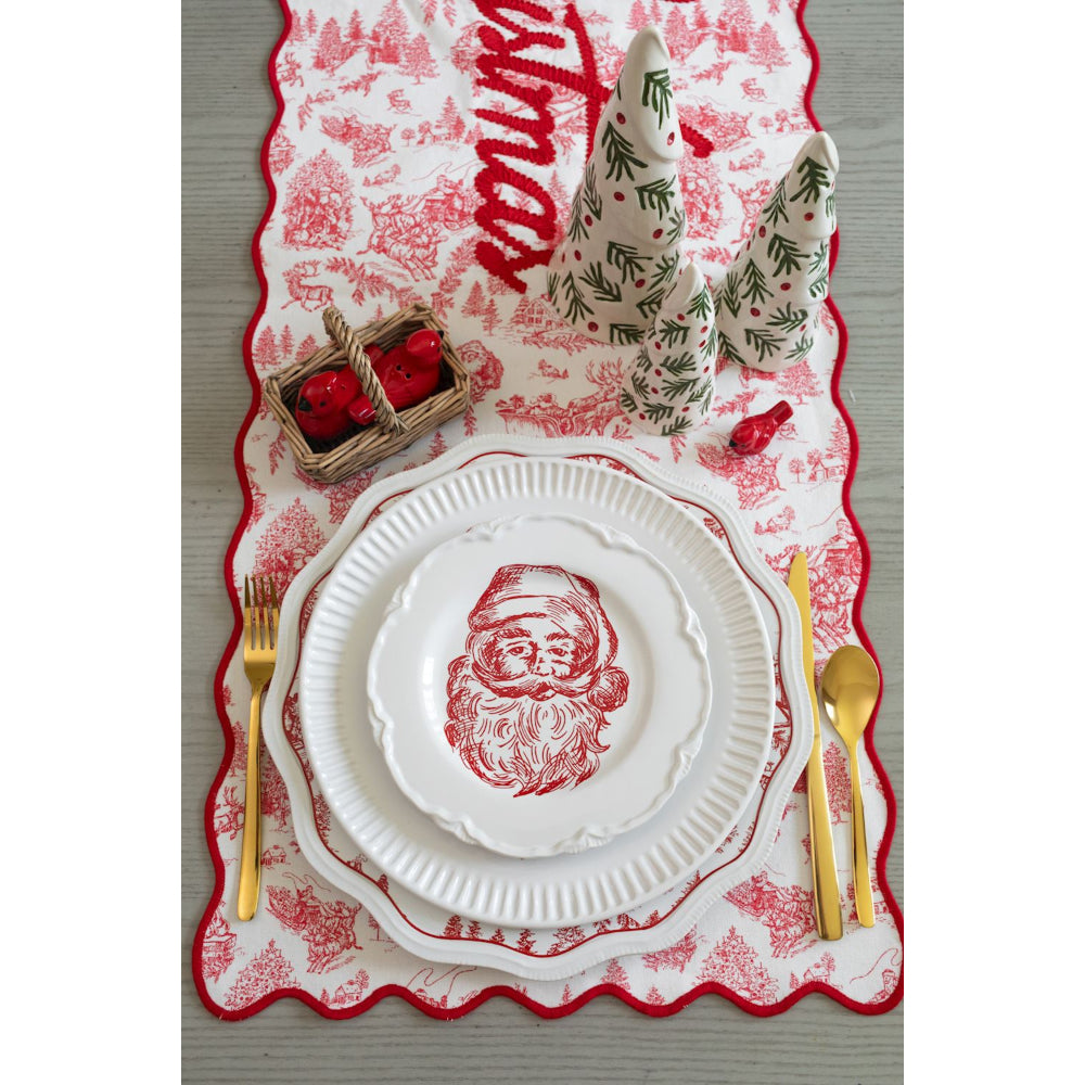 Christmas-themed table setting with Santa Claus design on plates and red and white patterned placemat.