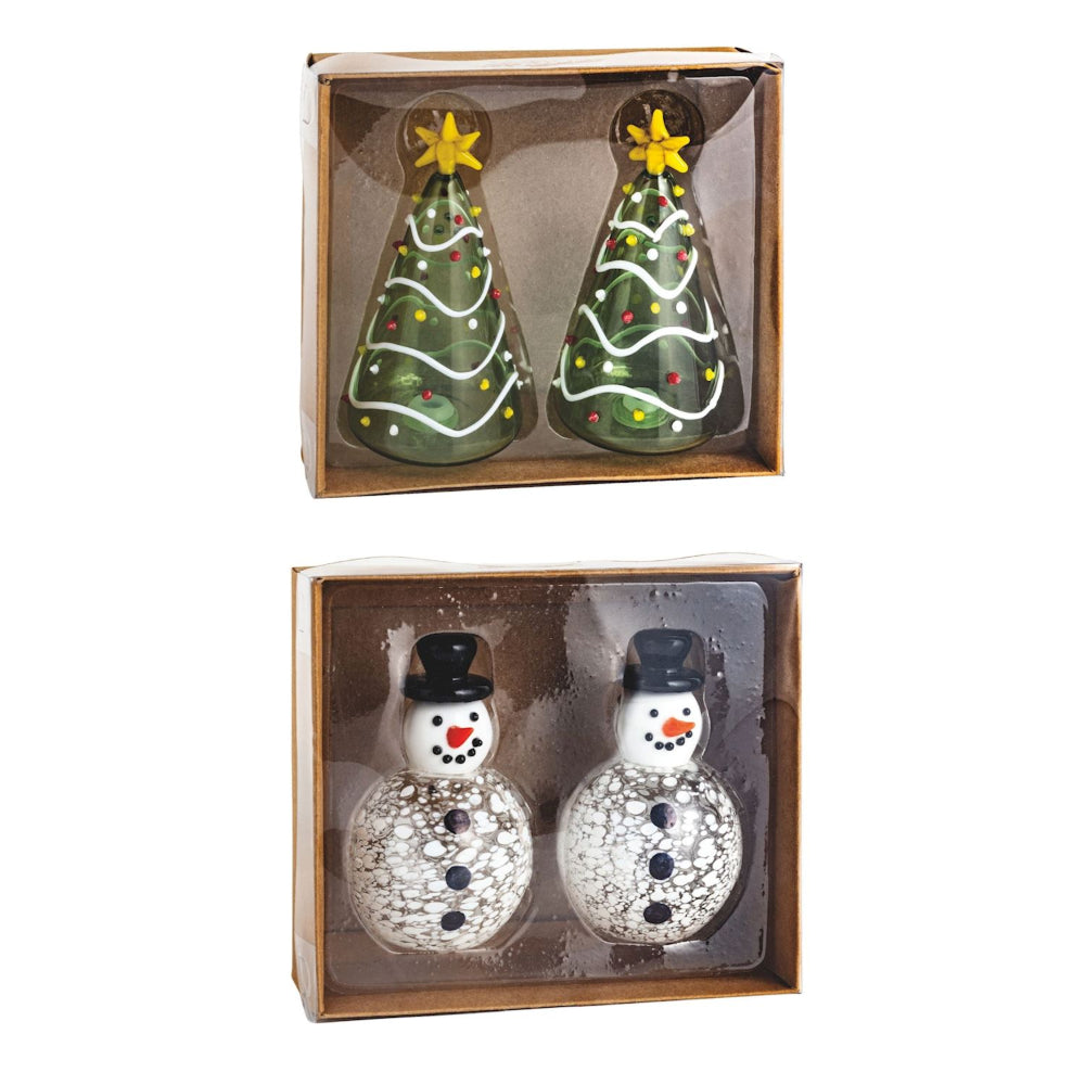 Two sets of Christmas-themed condiment shakers in packaging on a white background