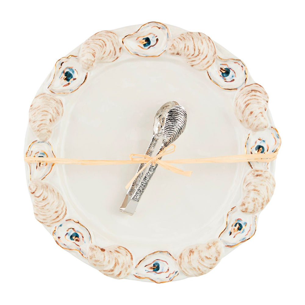 Decorative plate with a oyster shell design and a spoon on a white background.