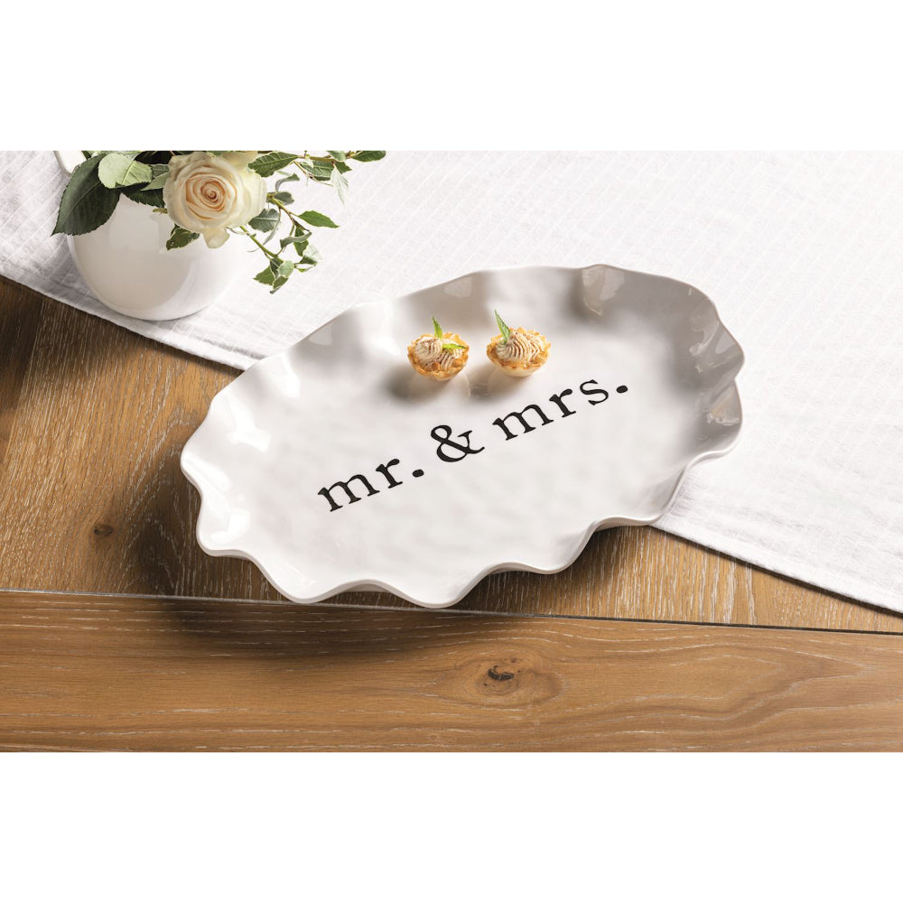 Silver 'mr. & mrs.' jewelry dish with earrings on a wooden surface.