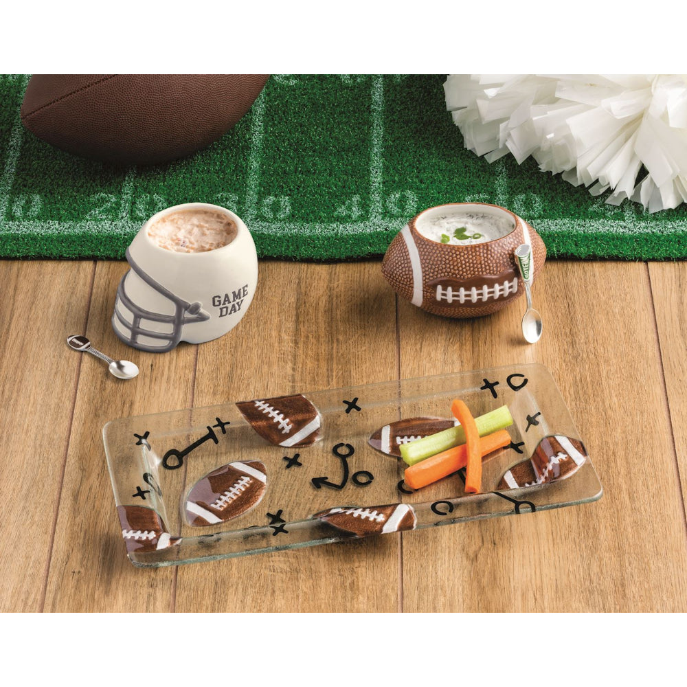 Football-themed snack platter with football-shaped bowls and a glass tray on a wooden surface.