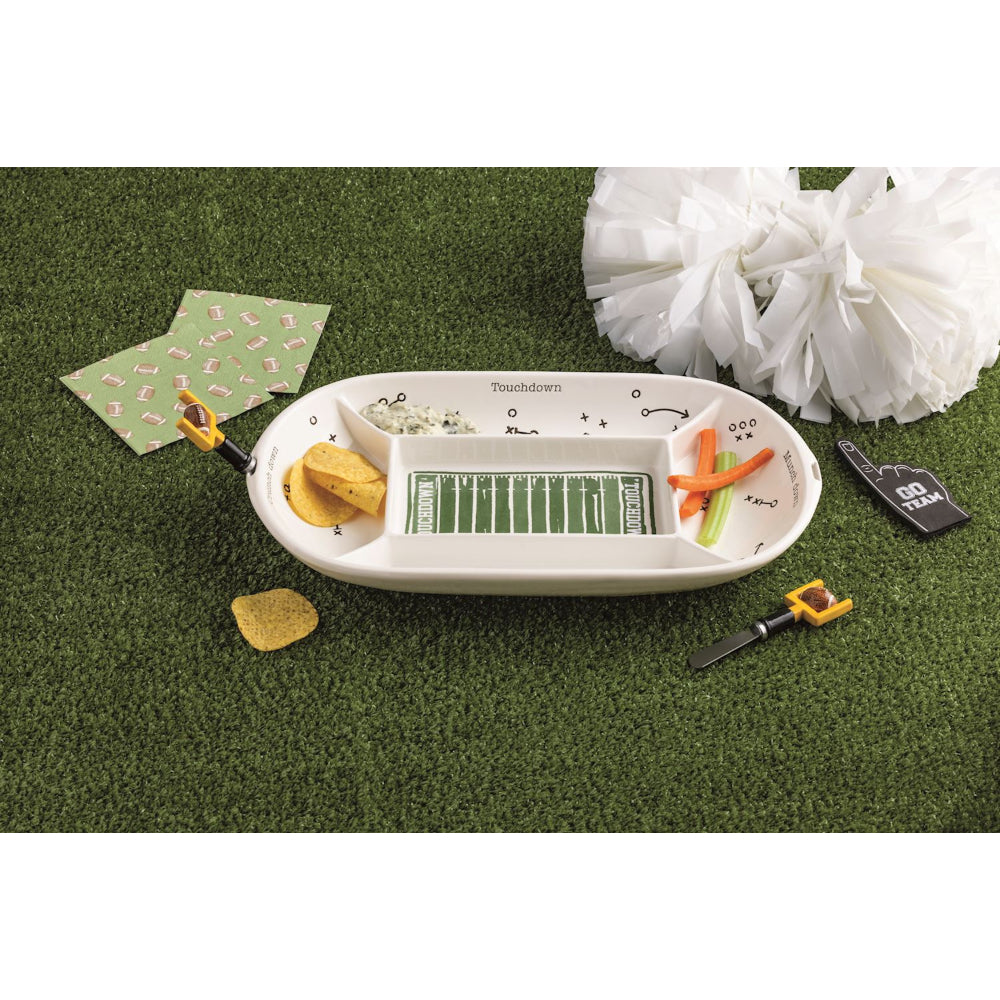 Football-themed snack platter with chips, pretzels, and decorative items on a green surface.