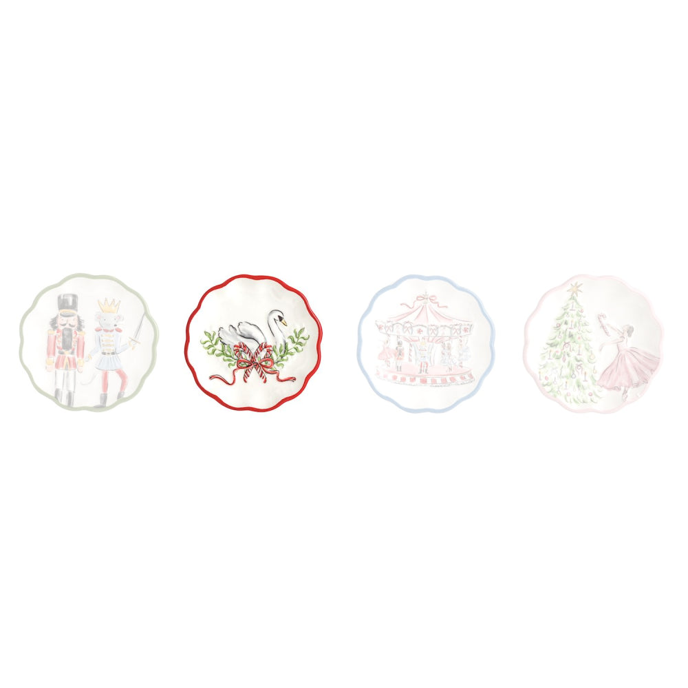 Four decorative ceramic plates with scalloped edges, each featuring a different whimsical illustration on a white background: a nutcracker and princess, a red-bordered swan with greenery, a carousel, and a ballerina dancing under a Christmas tree.