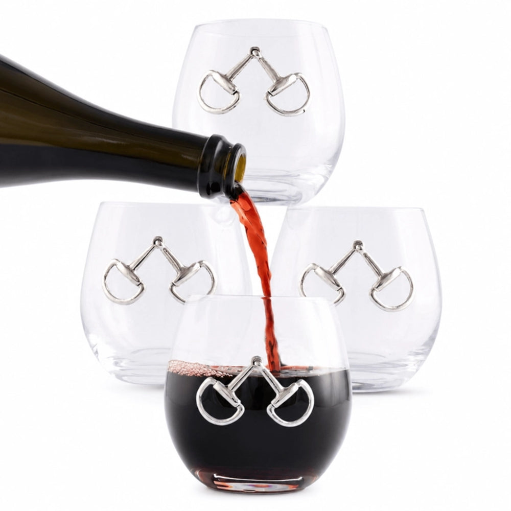 Three clear stemless wine glasses with silver horsebit-shaped metal accents, shown on a white background with red wine being poured from a dark bottle into the front glass.