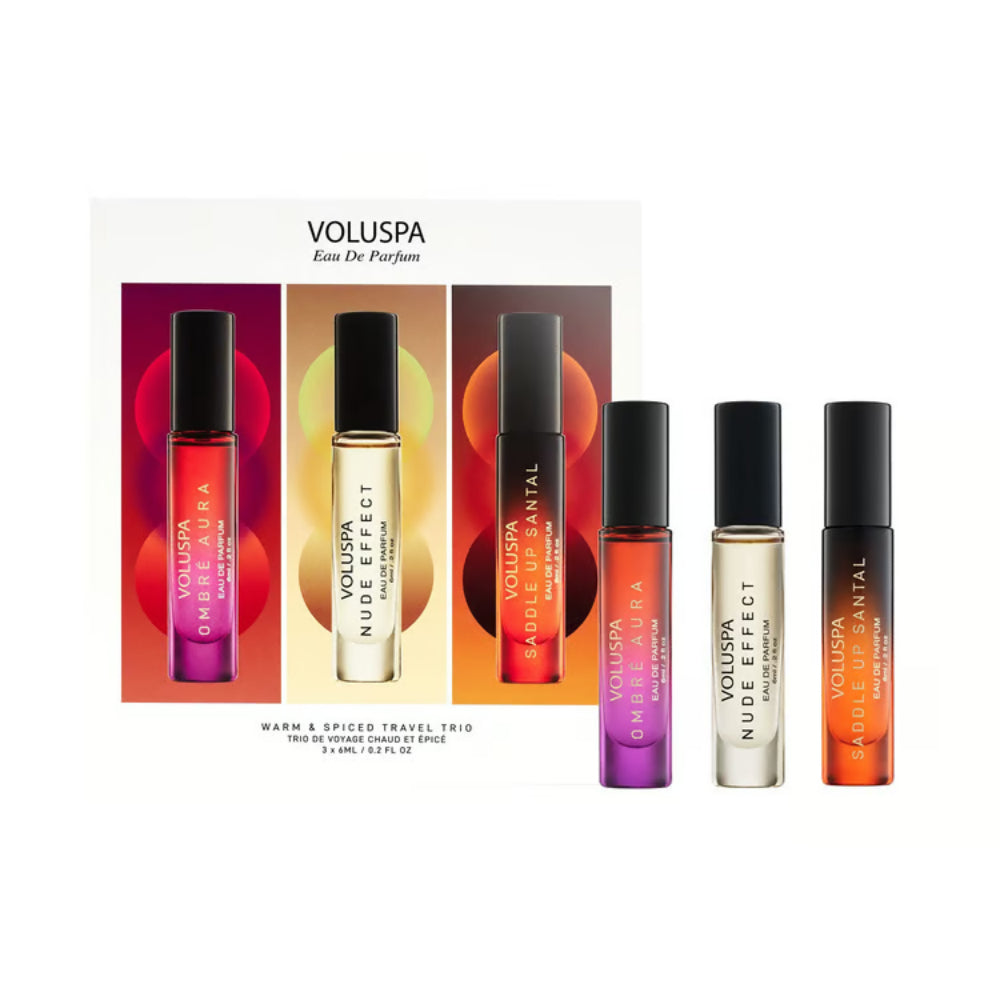 Voluspa Eau De Parfum Warm & Spiced Travel Trio set, featuring three 5 ml travel perfume atomizers with black caps and colorful gradient bottles, displayed alongside their white and multicolor packaging box on a clean white background.
