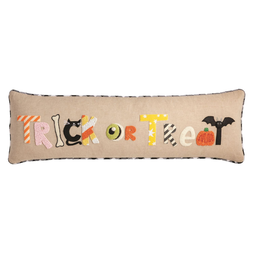 Tan pillow with Trick or Treat text in colorful halloween themed accents on a white backround. 