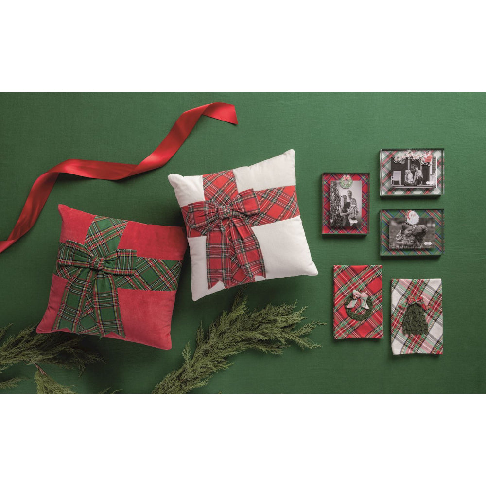 Decorative pillows with plaid patterns and a red ribbon on a green background.