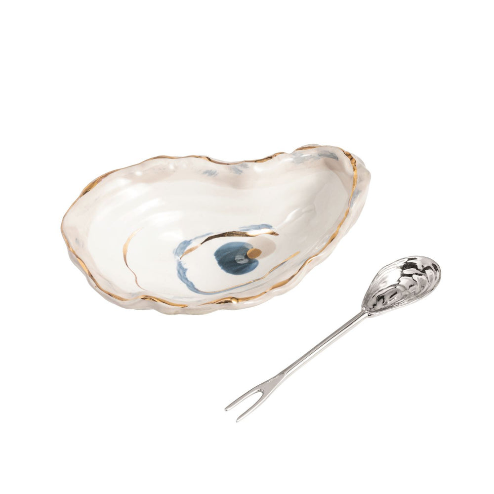 Ceramic oyster shell dish with decorative elements and a silver spoon on a white background.