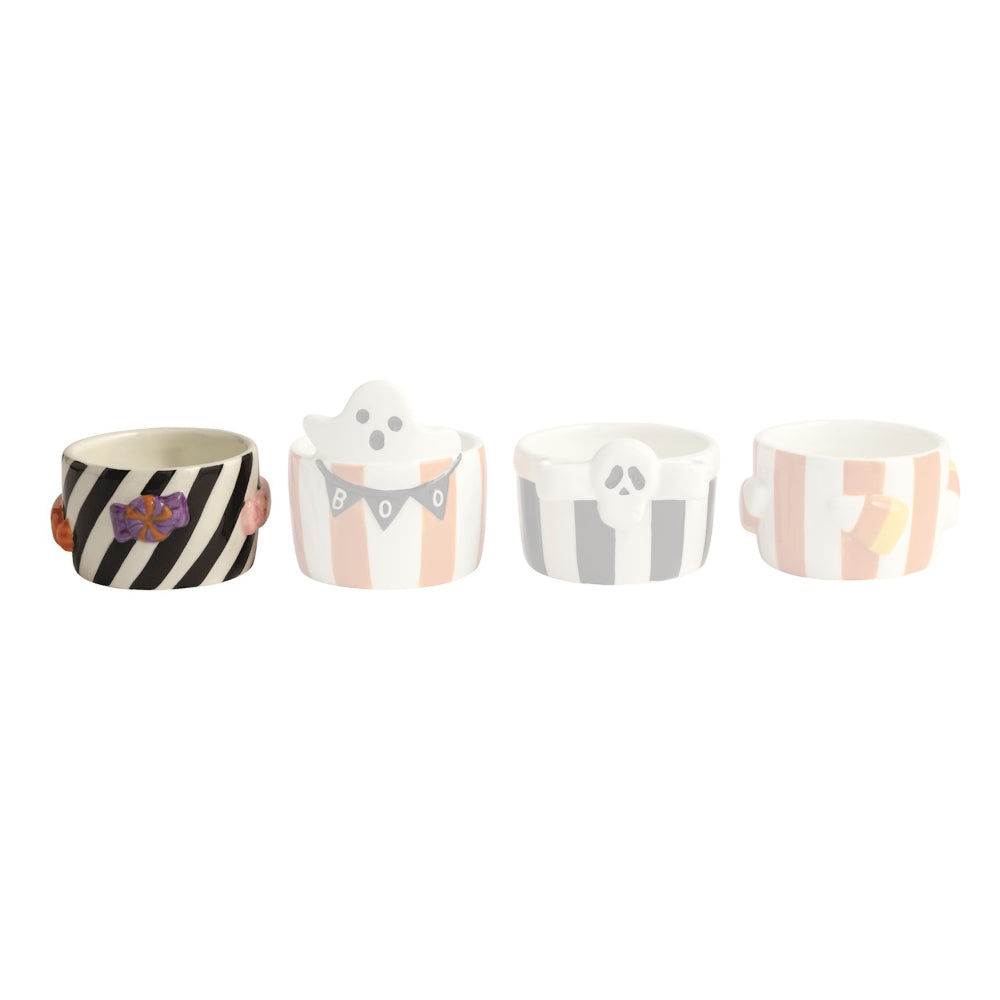 Four Halloween-themed ceramic cups with different designs on a white background