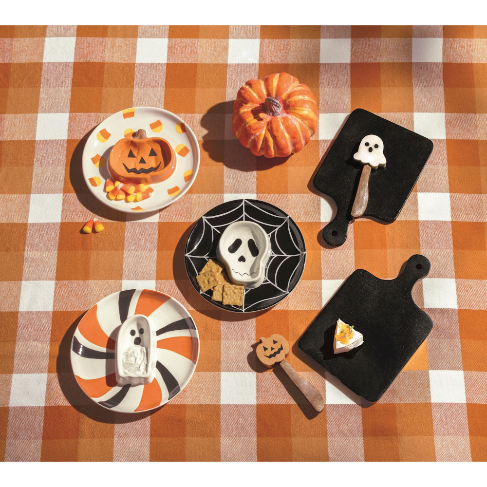 Halloween-themed plates and cutting boards on a checkered tablecloth