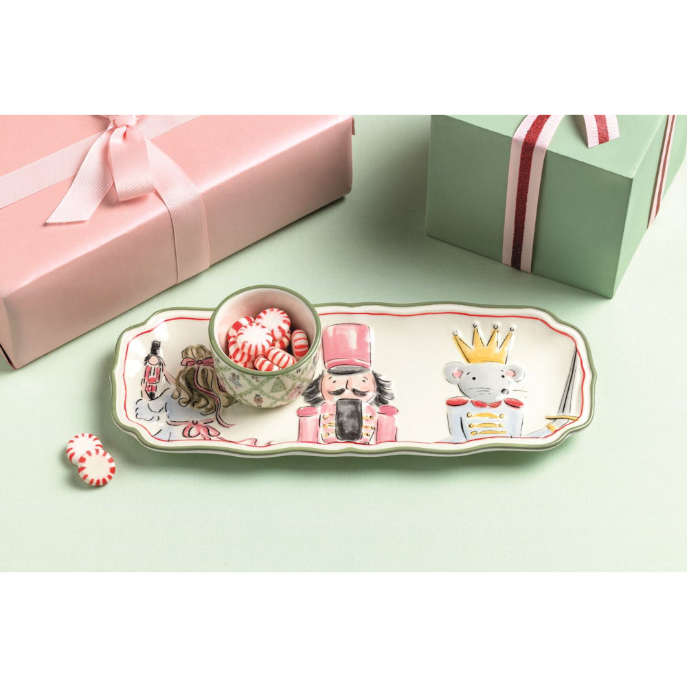 Decorative tray with cartoon characters and a small bowl on a light green surface, with gift boxes in the background.
