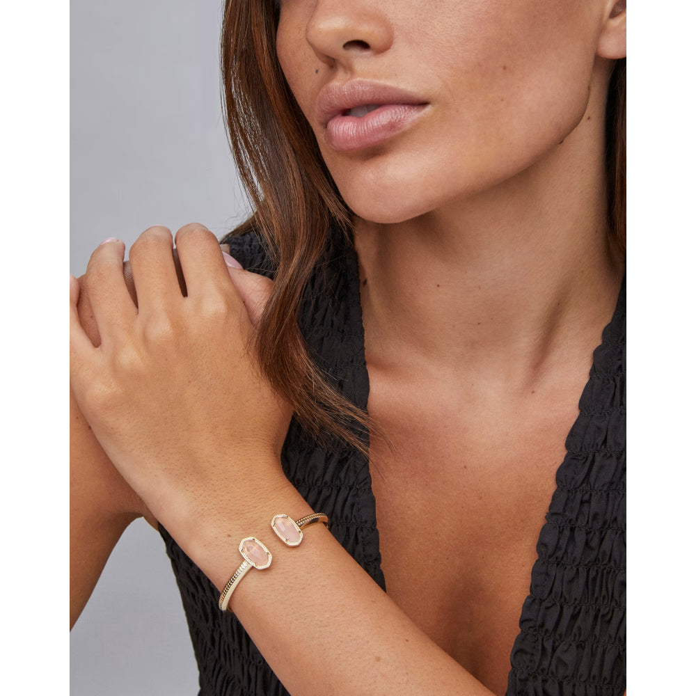 Woman wearing a gold bracelet with a gray background