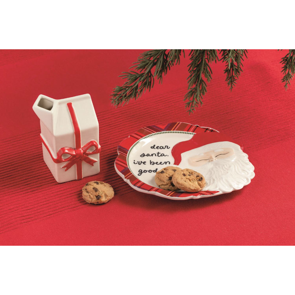 Christmas-themed plate with cookies, milk, and a gift on a red background.