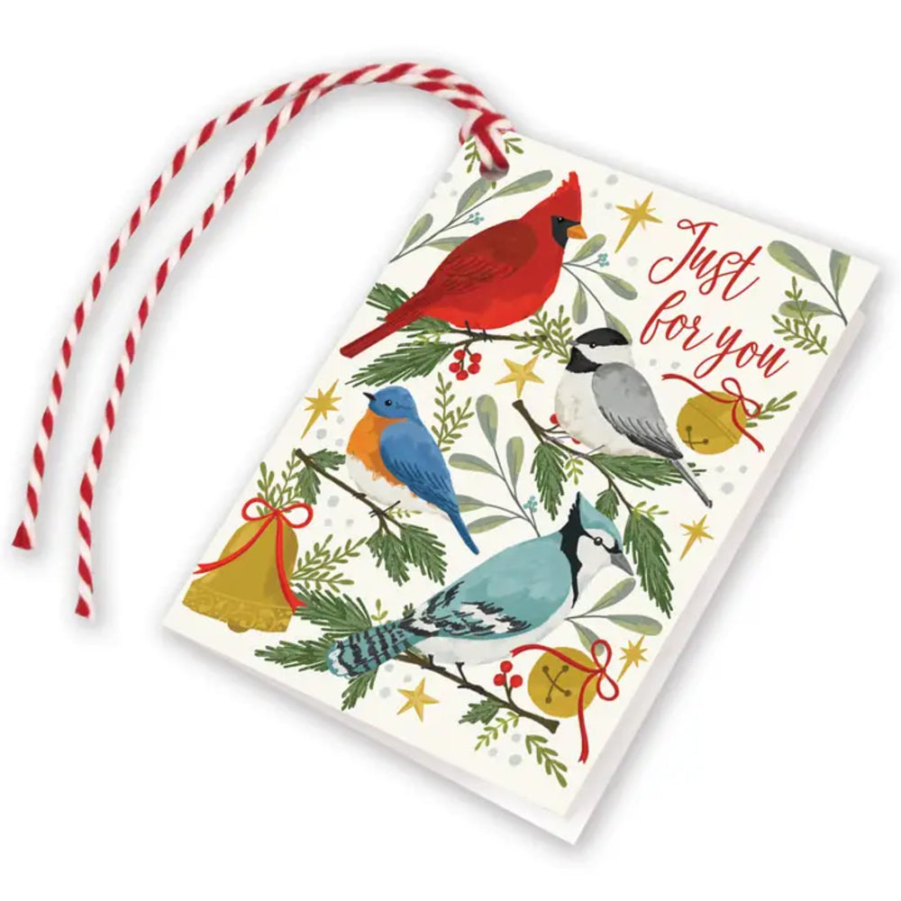 A Christmas greeting card with a red and white striped hanging ribbon, featuring illustrated birds, evergreen branches, bells, stars, and the words 'Just for you' on a white background.