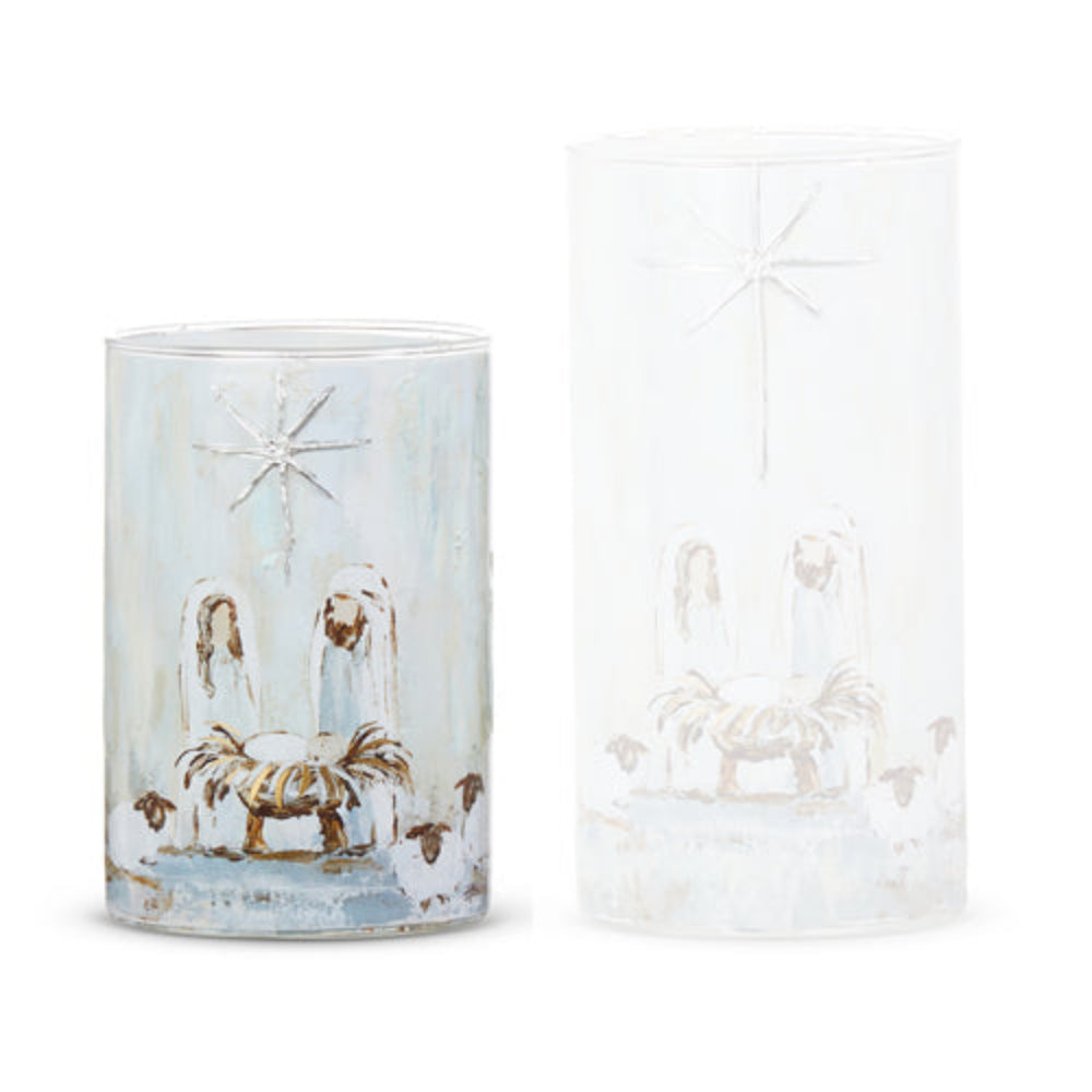 Small cylindrical glass container with a Nativity scene design, one with a light blue wash and the other clear/frosted, shown on a white background.