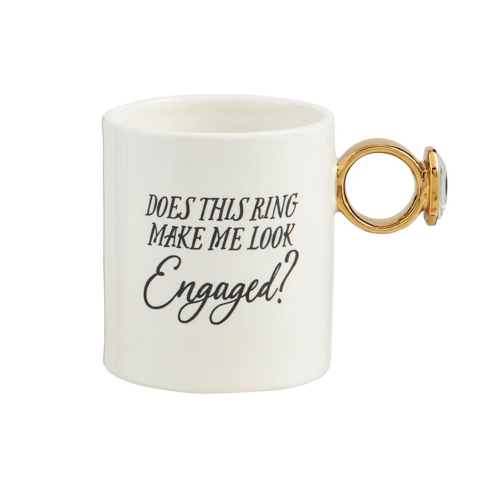 White mug with gold ring handle and text 'Does this ring make me look engaged?' on a white background.