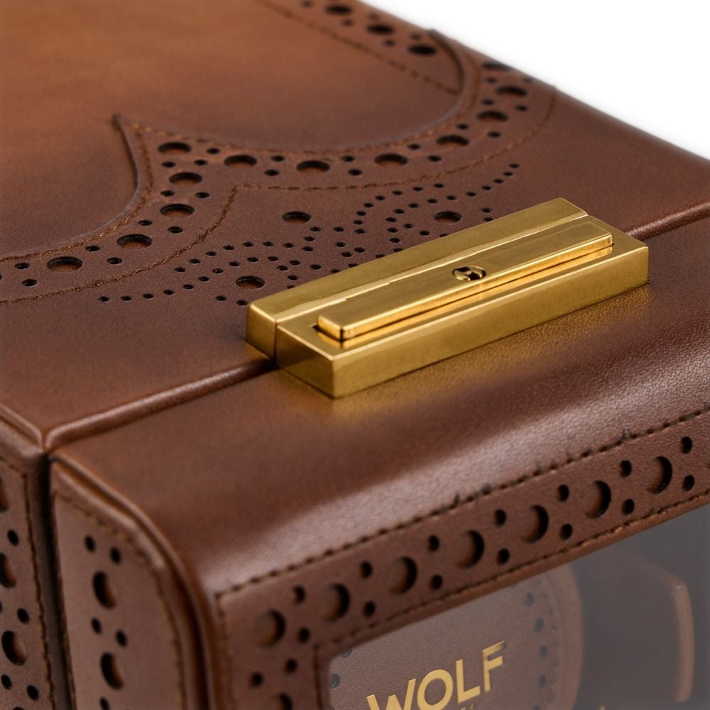Close-up of a brown leather box with gold clasp and 'WOLF' branding.