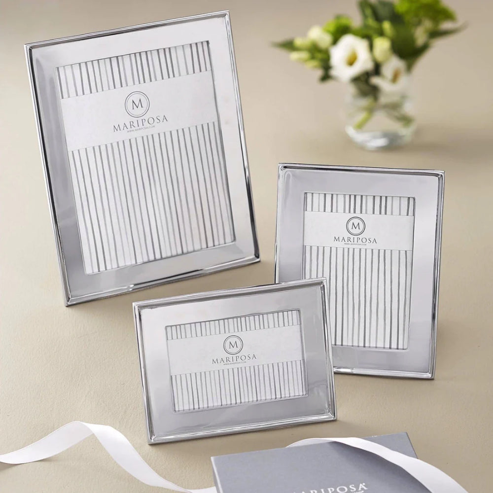 8x10, 5x7, 4x6 metallic silver frames on a beige table and  a vase with white flowers and a white ribbon. 