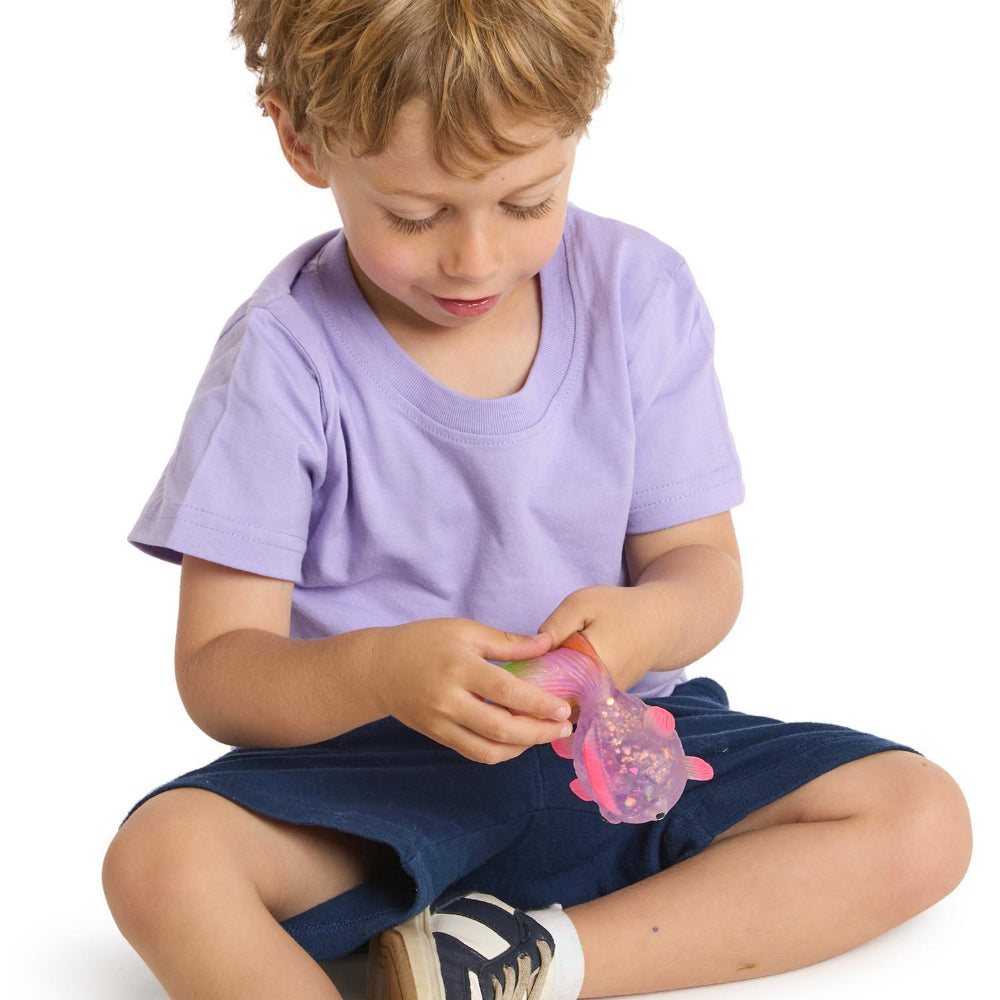 Child playing with a the pink glitter fish  on a white background