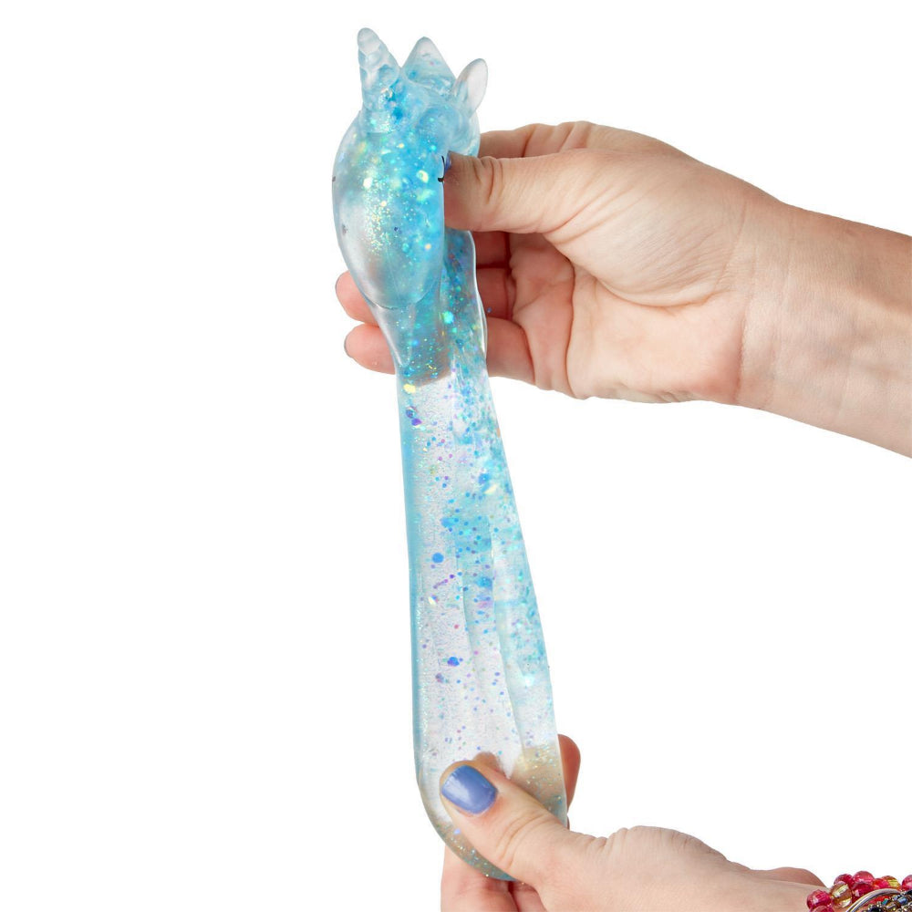 Hand stresing the  blue squishy glitter unicorn toy on a white backround 