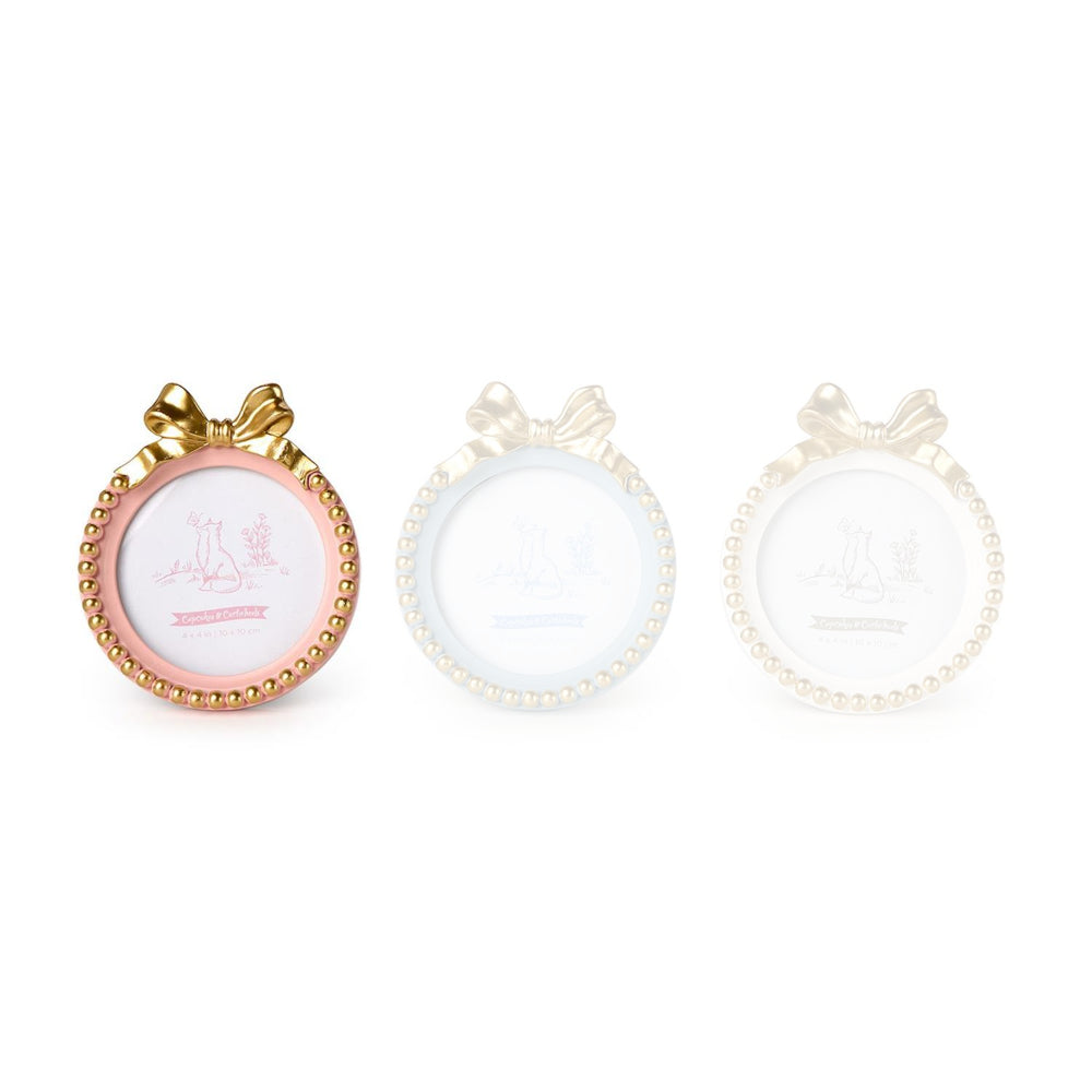Pink round golden bow picture frame with a decorative bow and bead trim on a white backround. 