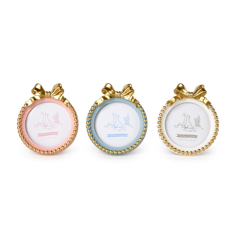 Three round decorative picture frames with gold beaded borders and bow details, shown side by side on a white background. The left frame is pink, the middle is light blue, and the right is white.