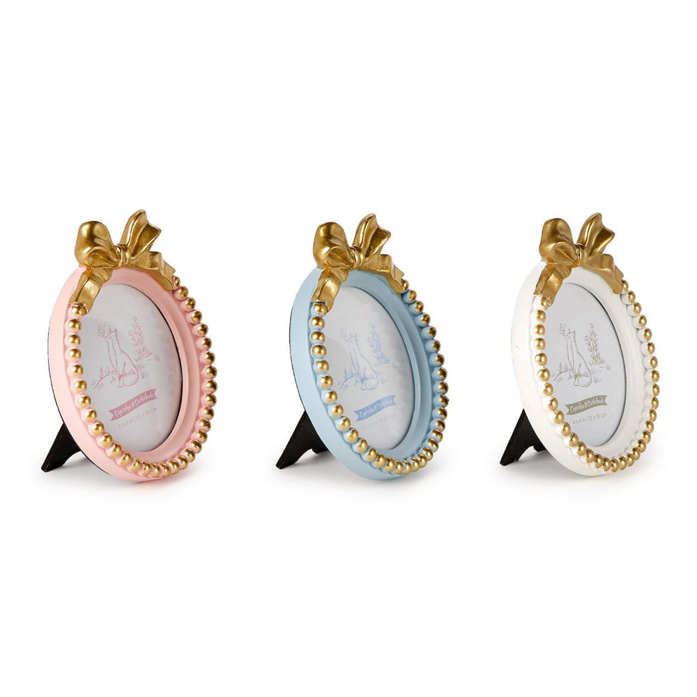 a side photo of three round picture frames with decorative bow and bead trim in pink, light blue, and white, each with a gold-tone bow and bead border, displayed on small black stands against a white background.