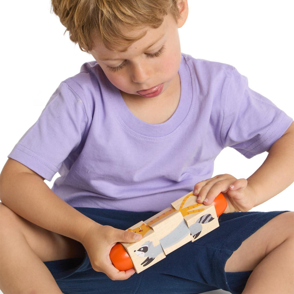 A boy in a purple shirt and blue shorts playing with a wooden toy on a white backround. 