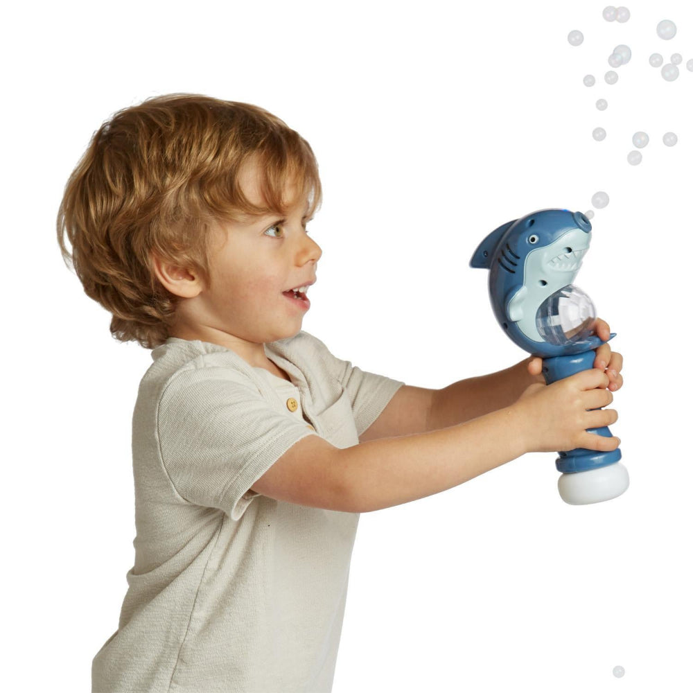 Child holding a shark-shaped bubble gun against a white background.